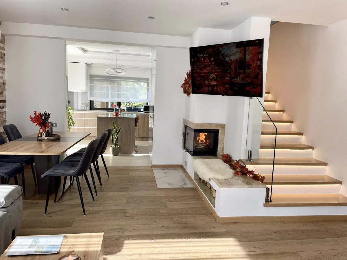 Living room with fireplace, LED staircase and view towards the kitchen