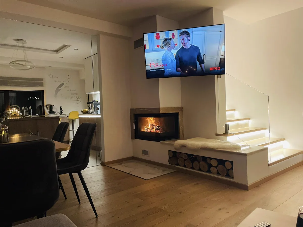 Living room at night with Netflix, fireplace and lit kitchen