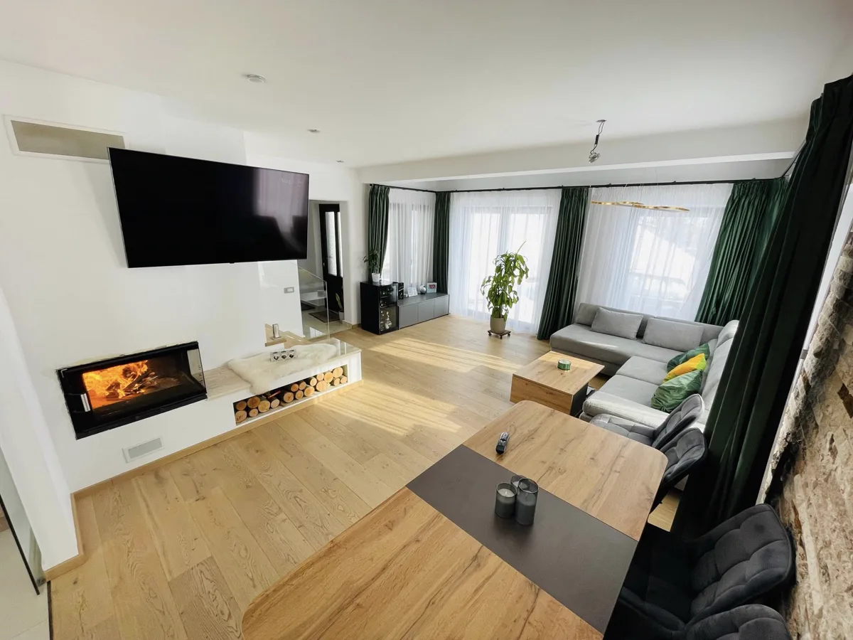 Spacious living room with green curtains and lit fireplace